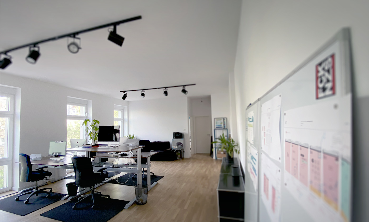 Leere Büroräume mit vier Computer-Arbeitsplätzen, bodentiefen Fenstern und Whiteboards
